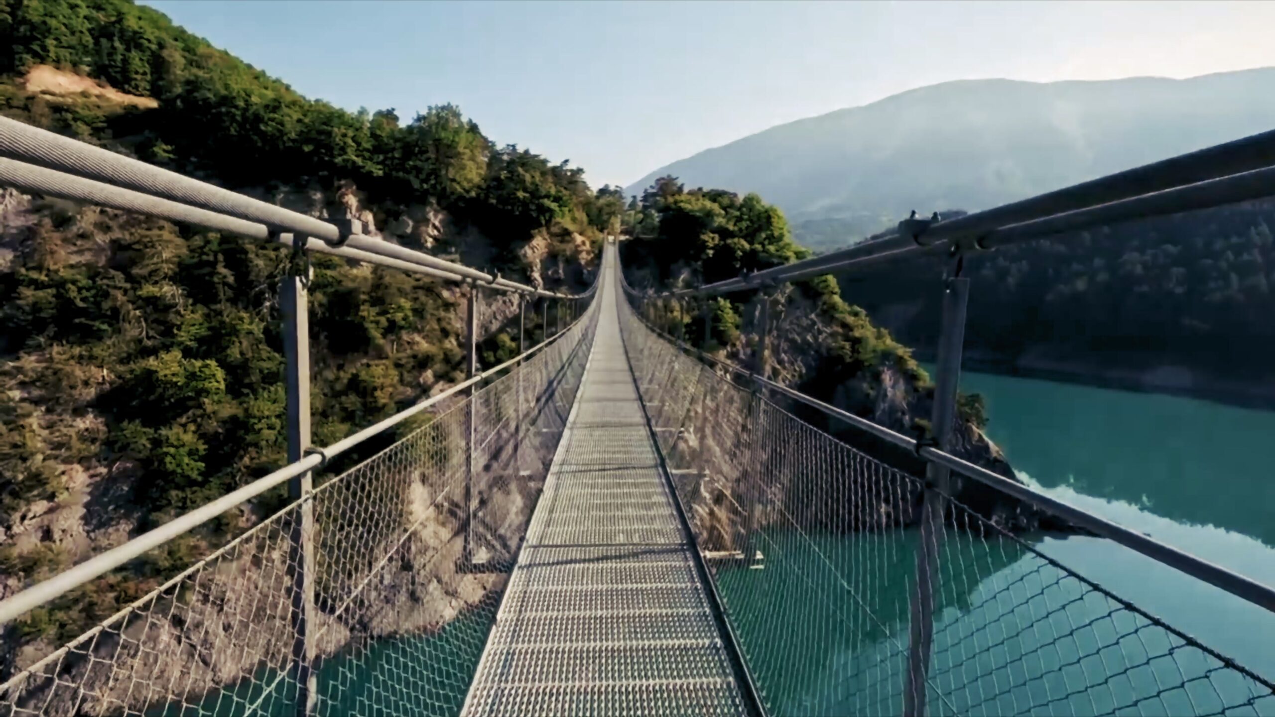 Passerelle suspendue au-dessus d’une rivière entre les reliefs