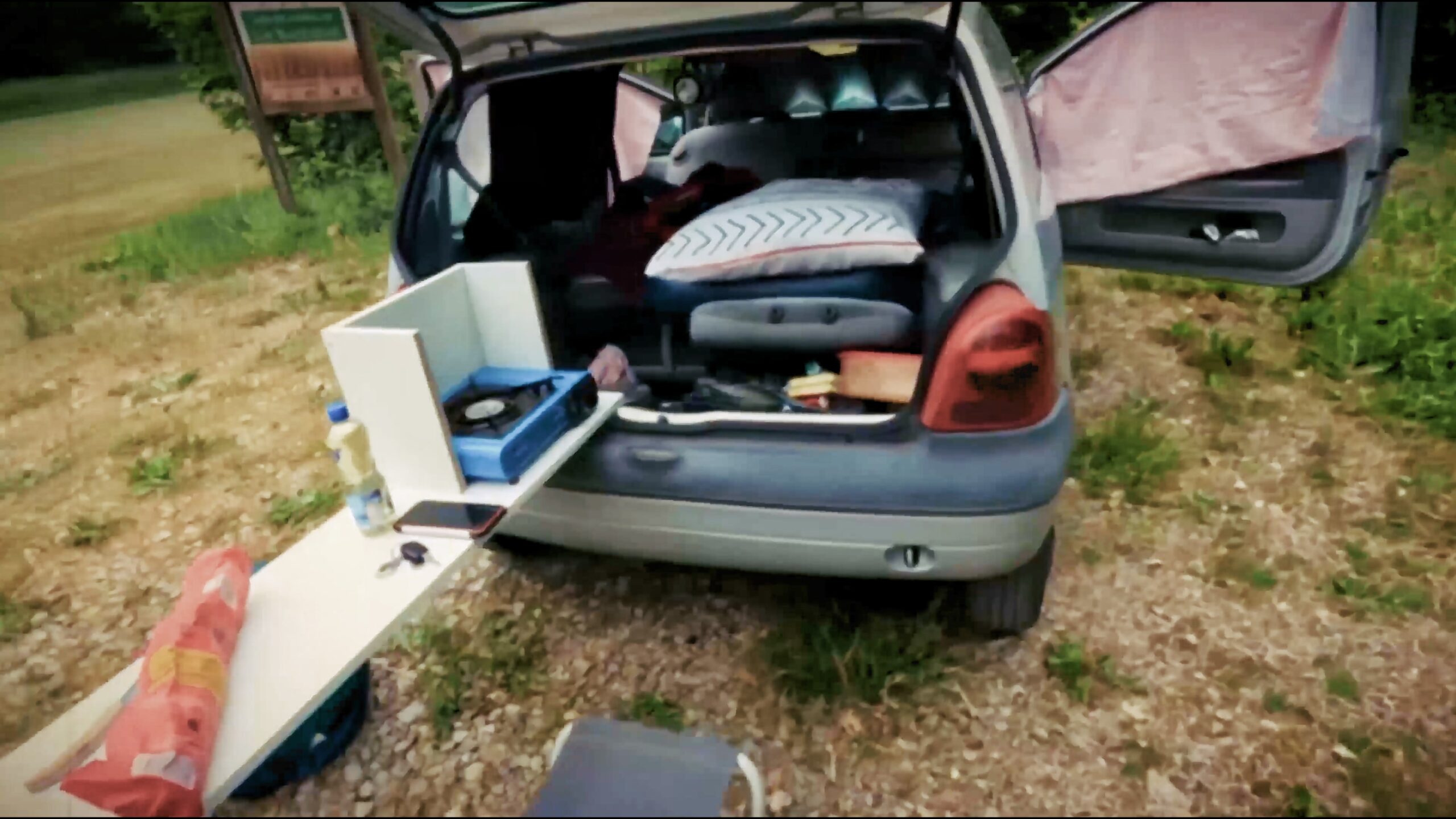 Coffre ouvert d’une Twingo avec le couchage et le matériel minimaliste