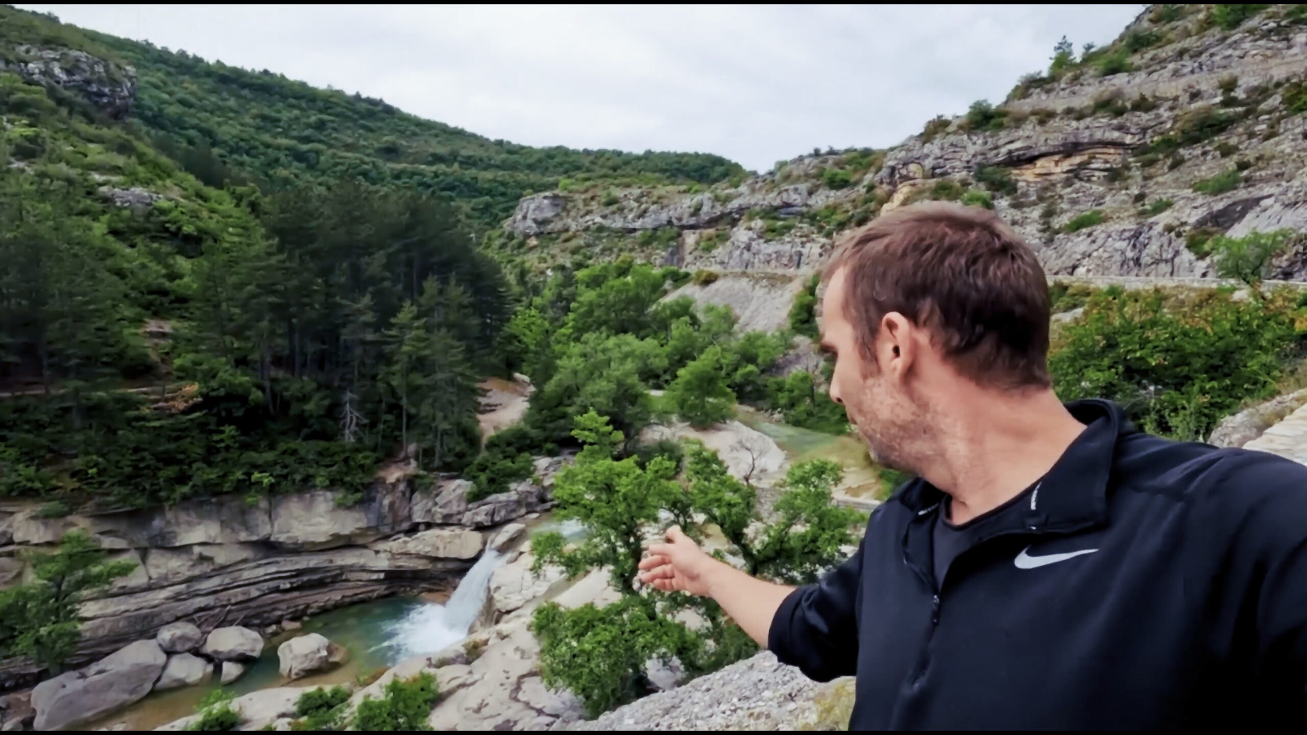 Voyageur devant une cascade dans un paysage de gorges
