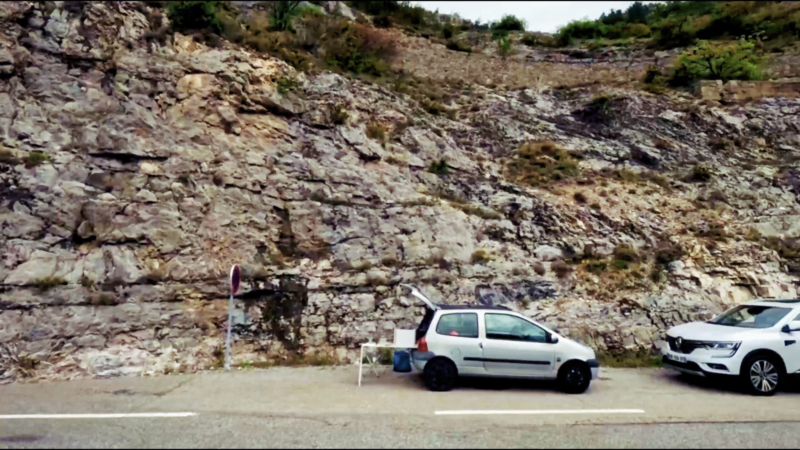 Twingo stationnée au bord d’une route au pied d’un paysage rocheux