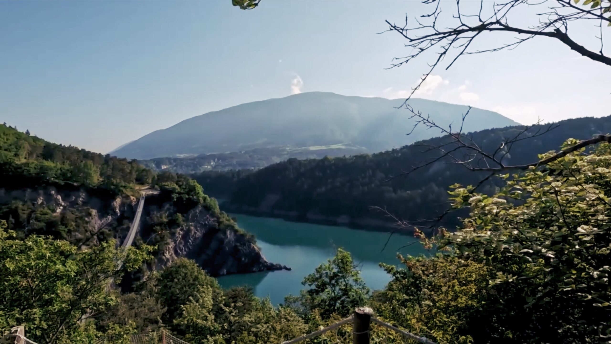 Vue sur un lac et les montagnes depuis un sentier boisé